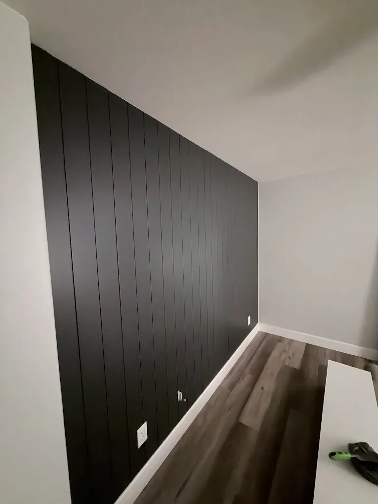 Floor-to-ceiling black vertical shiplap accent wall with new luxury vinyl plank flooring