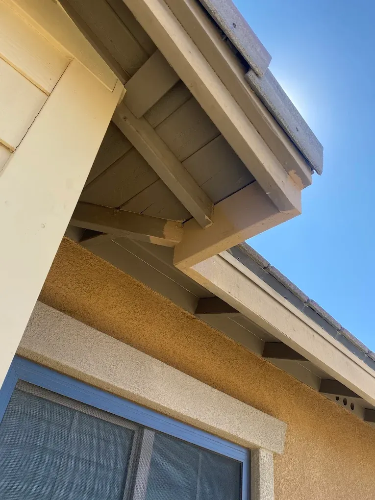 Exterior fascia and eave woodwork repaired and repainted along a roofline