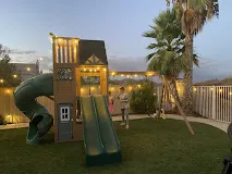 Backyard play structure assembled with landscape string lighting installed overhead